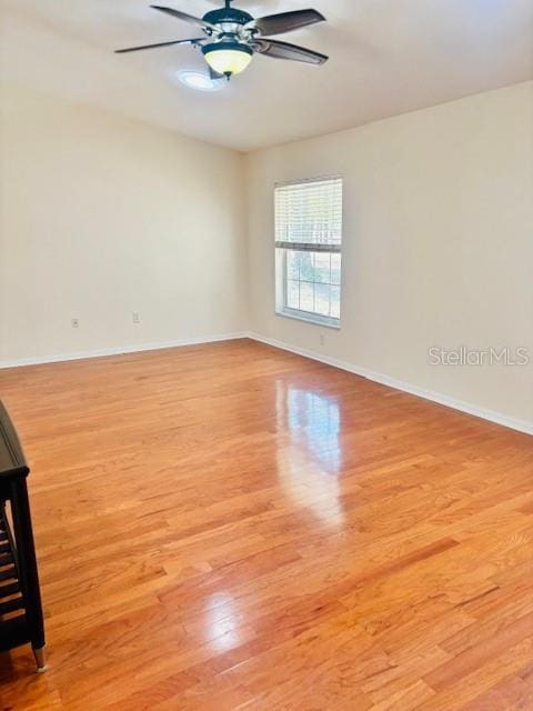 spare room with baseboards, light wood-style flooring, and a ceiling fan