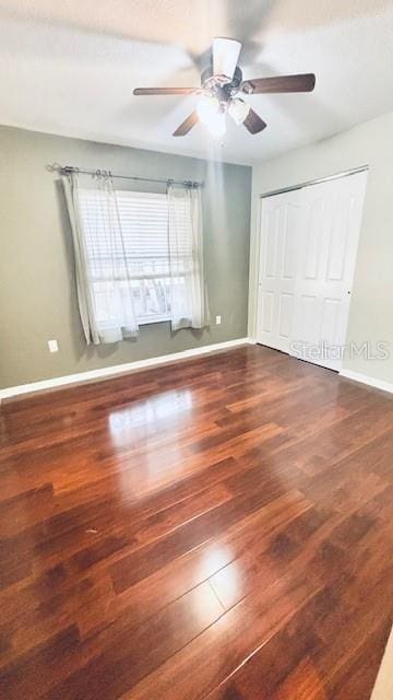 unfurnished bedroom featuring a closet, baseboards, and wood finished floors