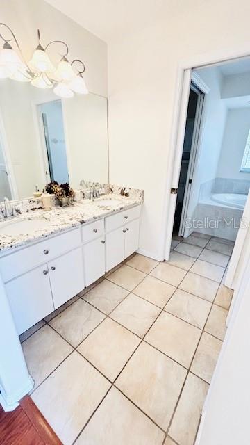 bathroom with double vanity, a garden tub, a sink, and tile patterned floors