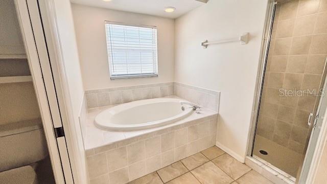 bathroom with a stall shower, tile patterned flooring, and a garden tub