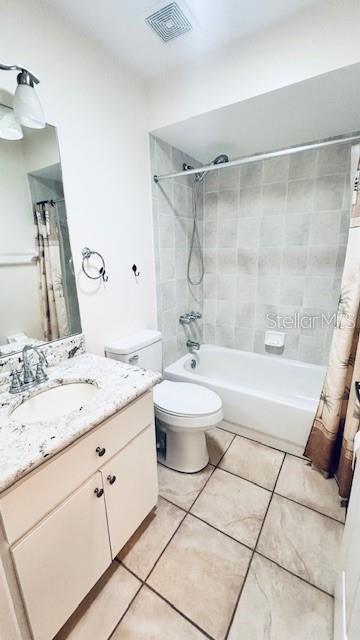 bathroom featuring visible vents, shower / bathtub combination with curtain, toilet, vanity, and tile patterned flooring