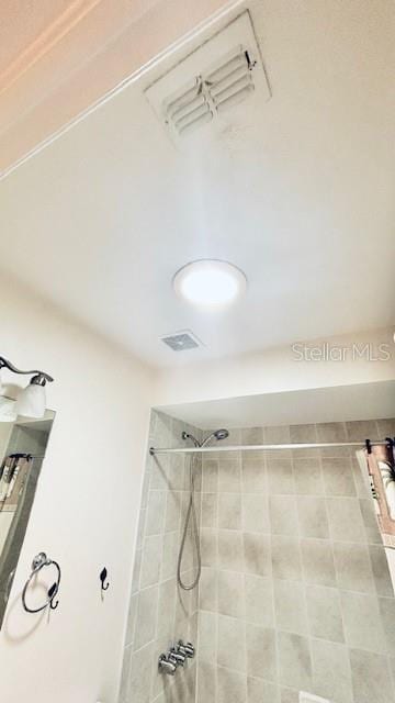 bathroom with visible vents and a tile shower