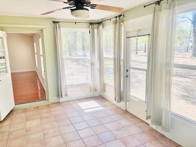 unfurnished sunroom featuring ceiling fan