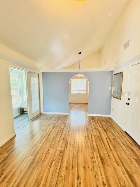 unfurnished living room featuring light wood-style floors, plenty of natural light, visible vents, and baseboards