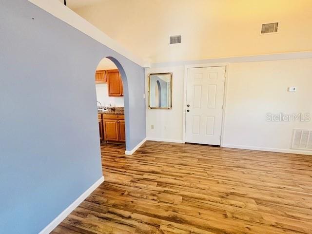 spare room featuring visible vents, arched walkways, and wood finished floors