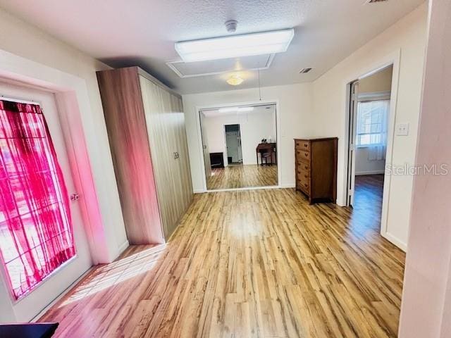 corridor with light wood-style floors, attic access, and baseboards