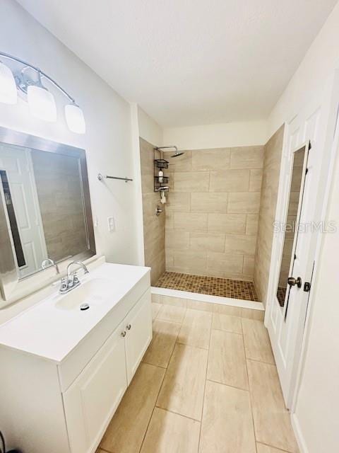 full bath with a tile shower and vanity