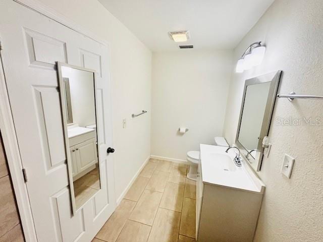 bathroom featuring wood finish floors, baseboards, vanity, and toilet