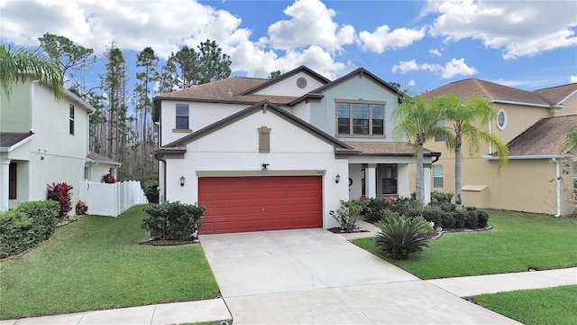 view of front facade with concrete driveway, a front yard, fence, and stucco siding