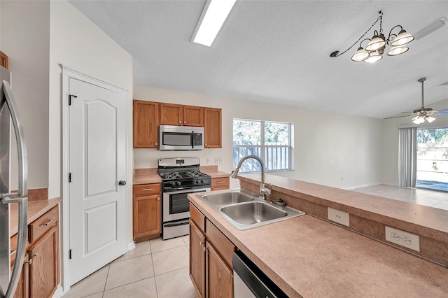 kitchen with pendant lighting, light tile patterned floors, light countertops, appliances with stainless steel finishes, and a sink