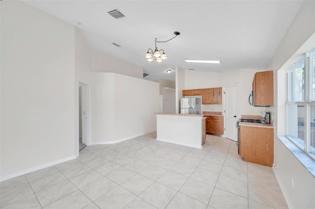 kitchen featuring light countertops, appliances with stainless steel finishes, brown cabinets, an inviting chandelier, and pendant lighting