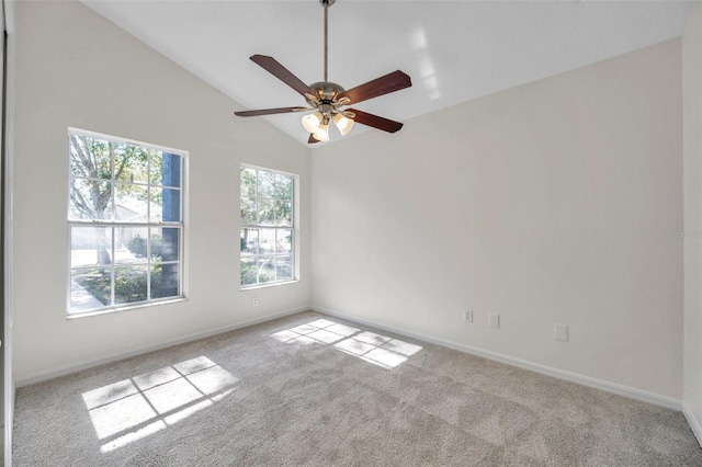 empty room with a ceiling fan, lofted ceiling, light colored carpet, and baseboards