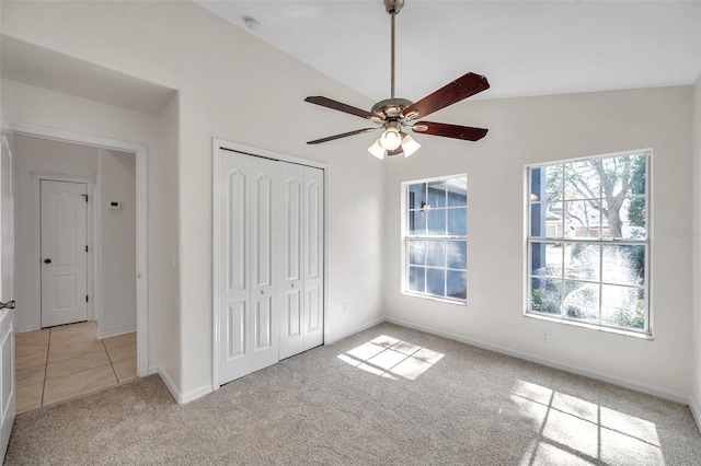 unfurnished bedroom with ceiling fan, light colored carpet, baseboards, vaulted ceiling, and a closet