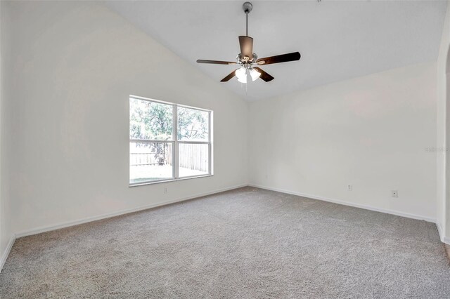carpeted empty room with baseboards, vaulted ceiling, and a ceiling fan