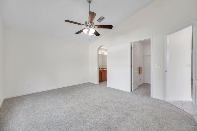 unfurnished bedroom with arched walkways, light colored carpet, visible vents, vaulted ceiling, and a spacious closet