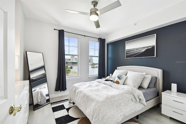 bedroom with light floors, a ceiling fan, and baseboards