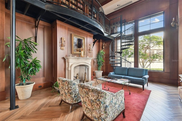 living area featuring stairway, wooden walls, a fireplace, and a towering ceiling