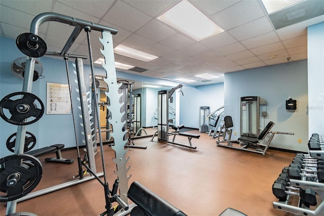 exercise room with baseboards and a drop ceiling