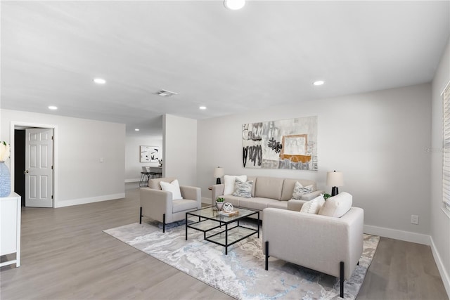 living room featuring baseboards, light wood finished floors, visible vents, and recessed lighting