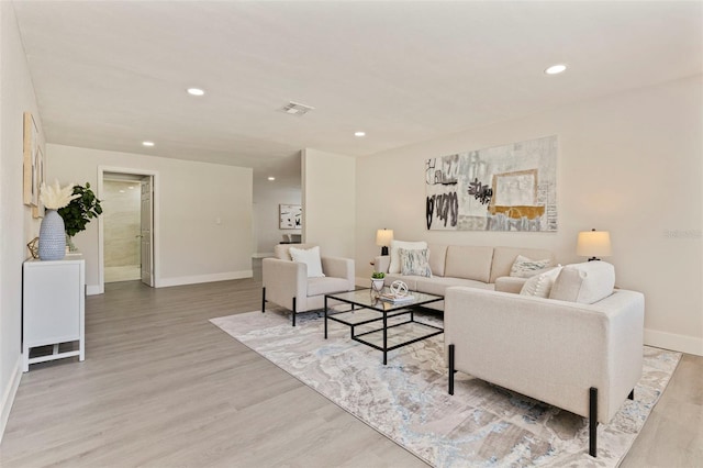 living room featuring baseboards, light wood finished floors, and recessed lighting