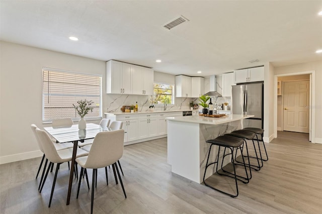 kitchen with baseboards, freestanding refrigerator, tasteful backsplash, and wall chimney range hood