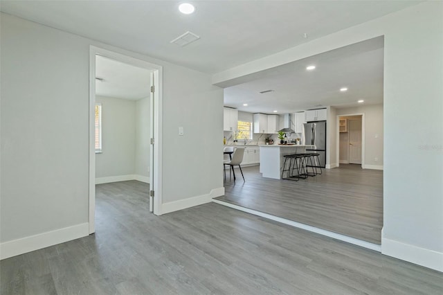 unfurnished living room featuring baseboards, light wood finished floors, and recessed lighting