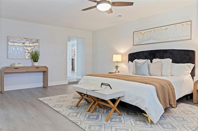 bedroom with baseboards, a ceiling fan, wood finished floors, and visible vents