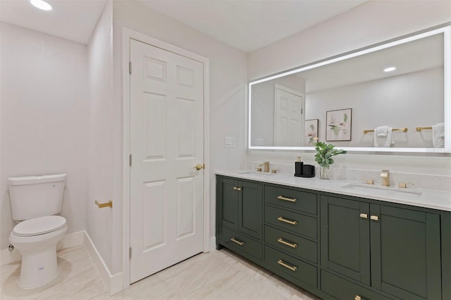 full bathroom featuring baseboards, a sink, double vanity, and toilet