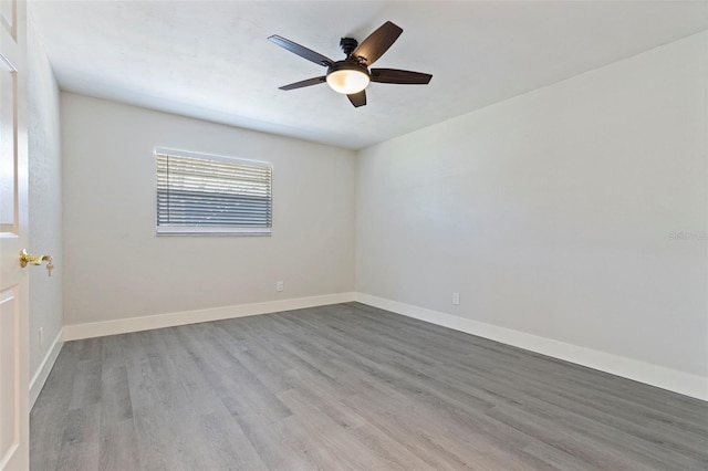 spare room featuring wood finished floors, a ceiling fan, and baseboards