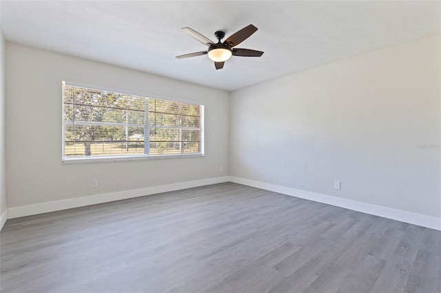 empty room with wood finished floors, a ceiling fan, and baseboards