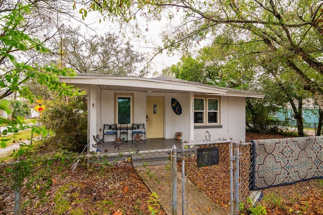 view of front of house featuring a porch, a fenced front yard, a gate, and stucco siding