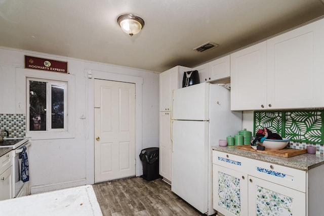 kitchen featuring wood finished floors, visible vents, white cabinetry, freestanding refrigerator, and decorative backsplash