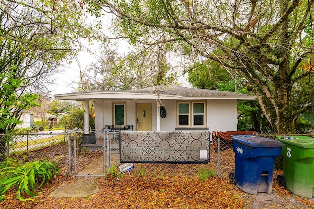 bungalow-style home featuring a porch, a fenced front yard, a gate, and stucco siding