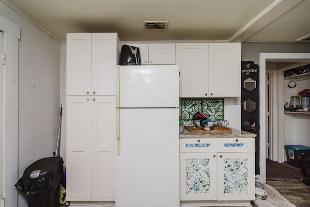 kitchen with visible vents, white cabinets, and freestanding refrigerator