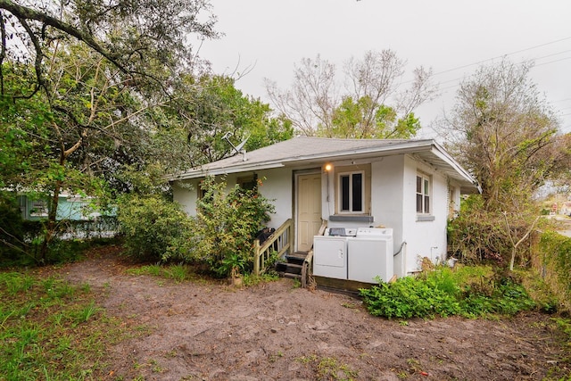 view of front facade with entry steps, washer / clothes dryer, and stucco siding