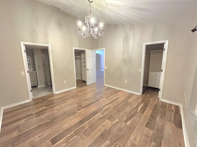 unfurnished bedroom with a closet, wood-type flooring, a walk in closet, and connected bathroom