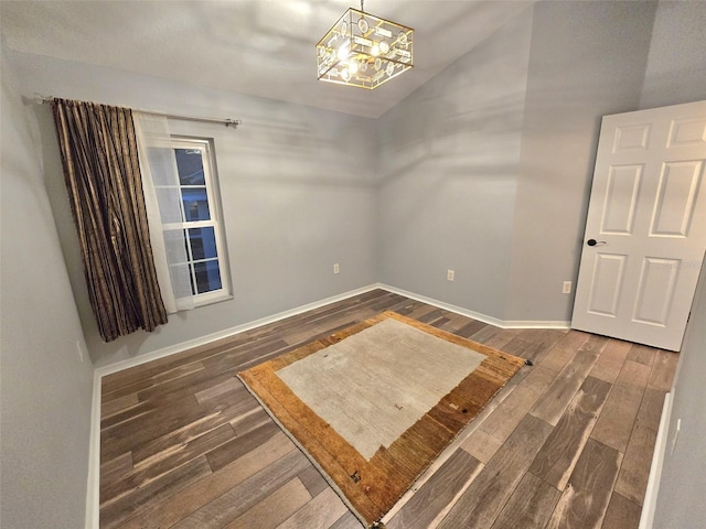 empty room featuring a notable chandelier, baseboards, and wood finished floors