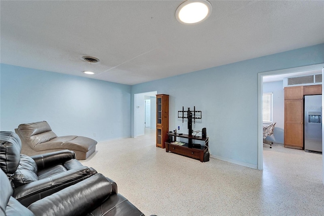 living area featuring light speckled floor, visible vents, and a textured ceiling