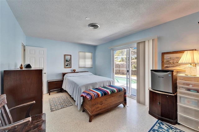 bedroom featuring access to exterior, visible vents, a textured ceiling, and speckled floor