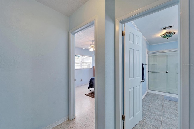 corridor featuring light speckled floor, visible vents, ornamental molding, and baseboards