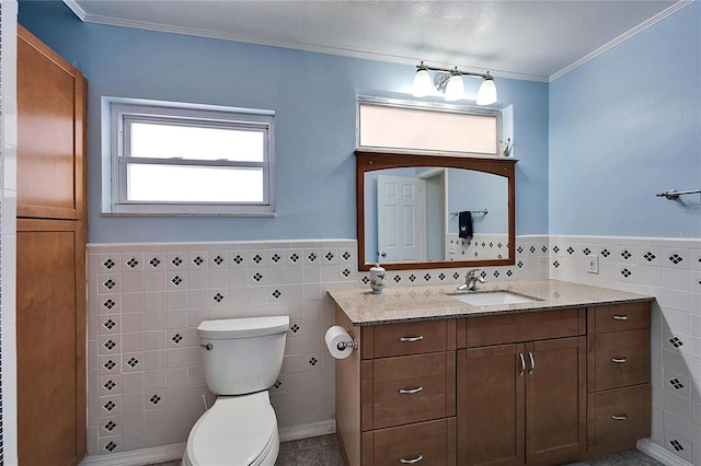 bathroom with a wainscoted wall, tile walls, toilet, ornamental molding, and vanity