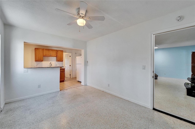 unfurnished living room with light speckled floor, a textured ceiling, a ceiling fan, and baseboards