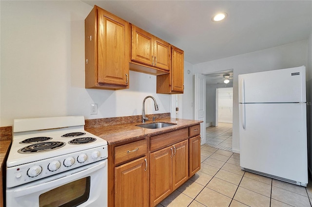 kitchen featuring light tile patterned floors, ceiling fan, white appliances, a sink, and brown cabinetry