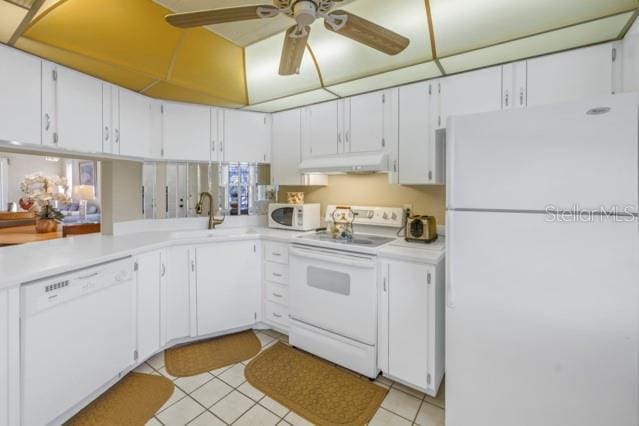 kitchen with light countertops, white appliances, a sink, and under cabinet range hood
