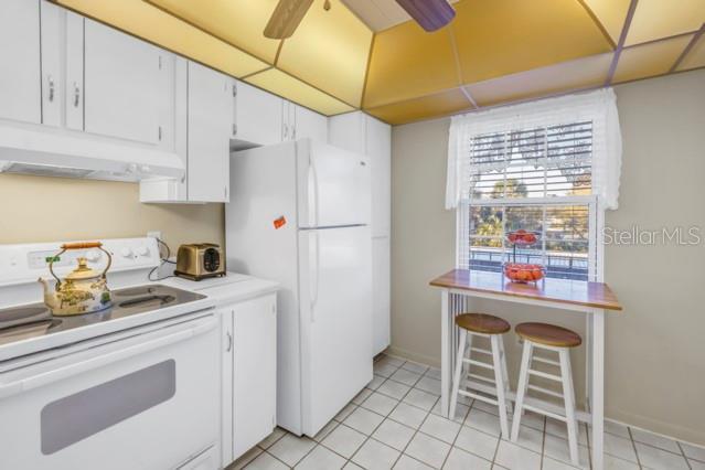 kitchen with under cabinet range hood, white appliances, a ceiling fan, white cabinetry, and light countertops
