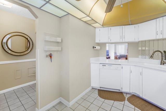 kitchen with light tile patterned floors, white cabinets, a ceiling fan, dishwasher, and light countertops