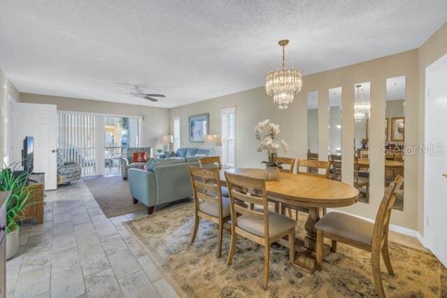 dining space featuring a textured ceiling and ceiling fan with notable chandelier
