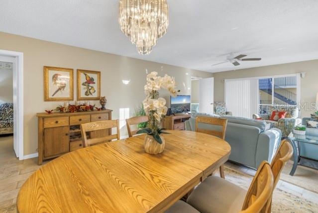 dining space with ceiling fan with notable chandelier