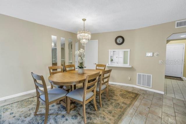 dining room with a chandelier, arched walkways, visible vents, and baseboards