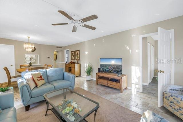 living area with ceiling fan with notable chandelier, visible vents, and baseboards